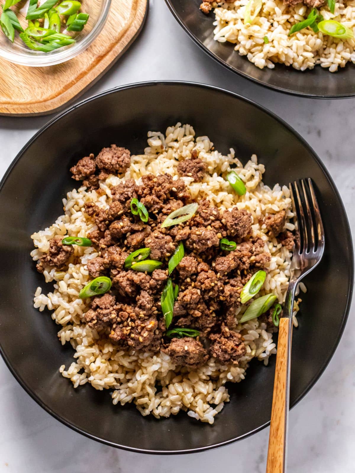 Healthy Korean beef bowl served up in a black bowl with a fork resting to the side and another bowl in the corner.