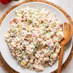 macaroni salad in a white bowl with wooden spoon