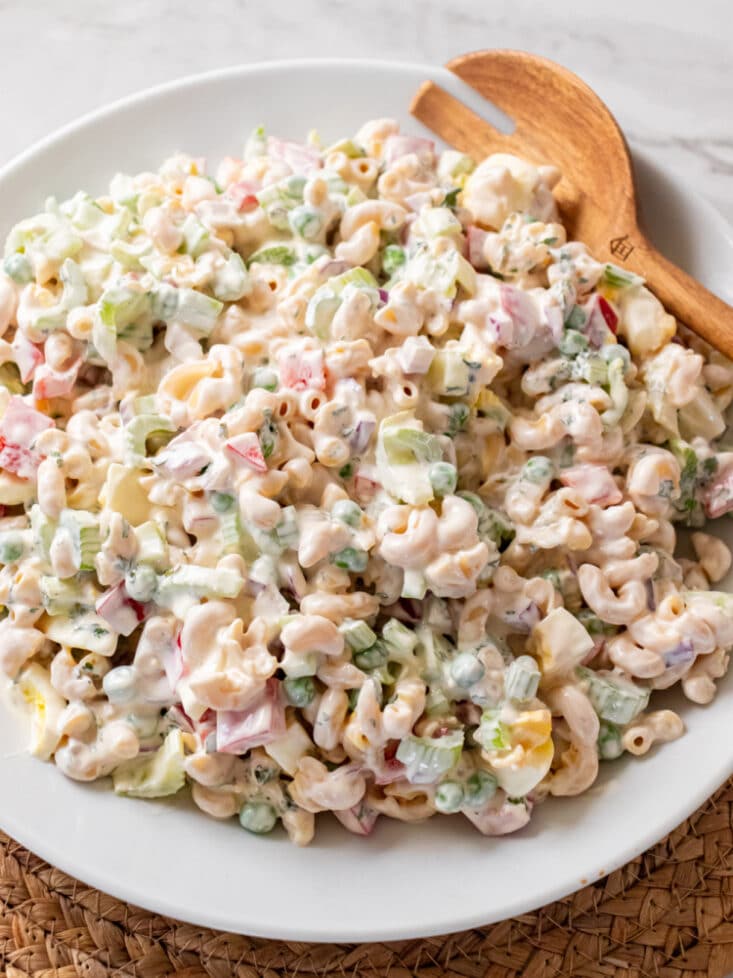 white bowl with macaroni pasta salad and a wooden spoon