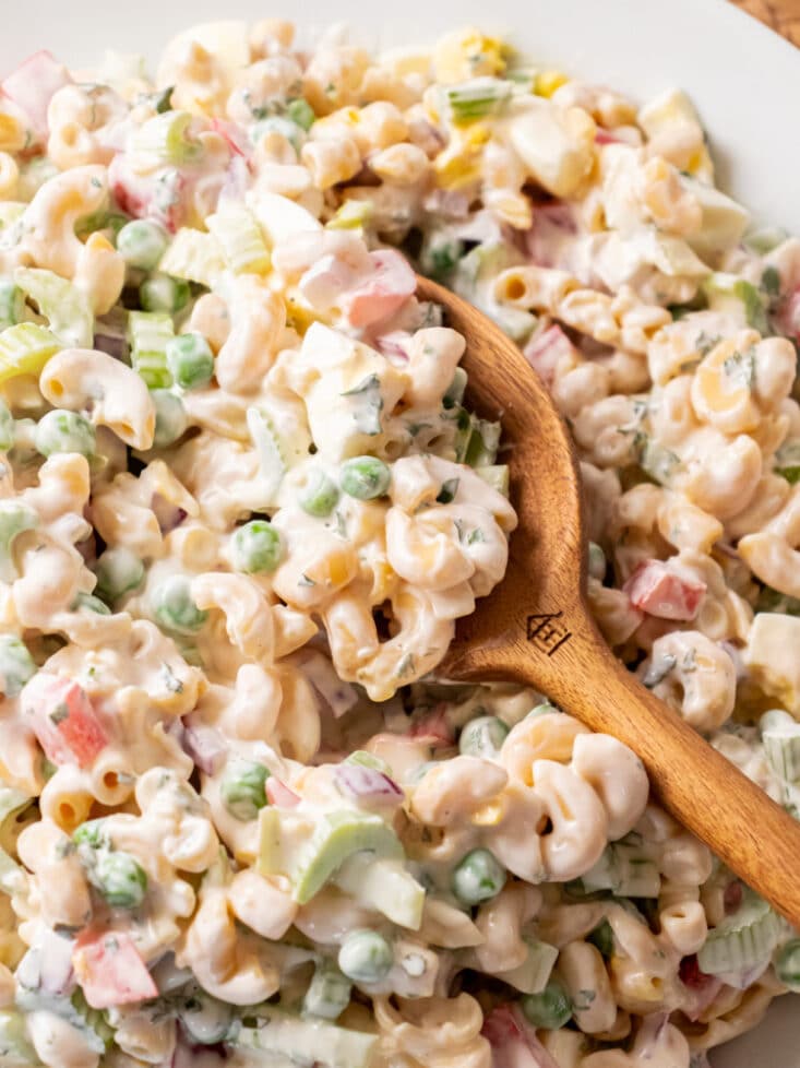 macaroni salad with peas on a wooden spoon