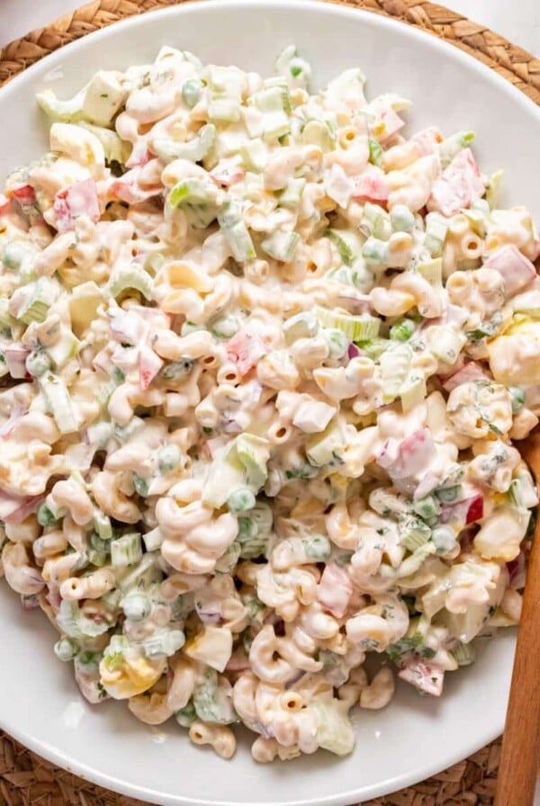 Healthy macaroni salad in a white bowl with wooden spoon to the side.
