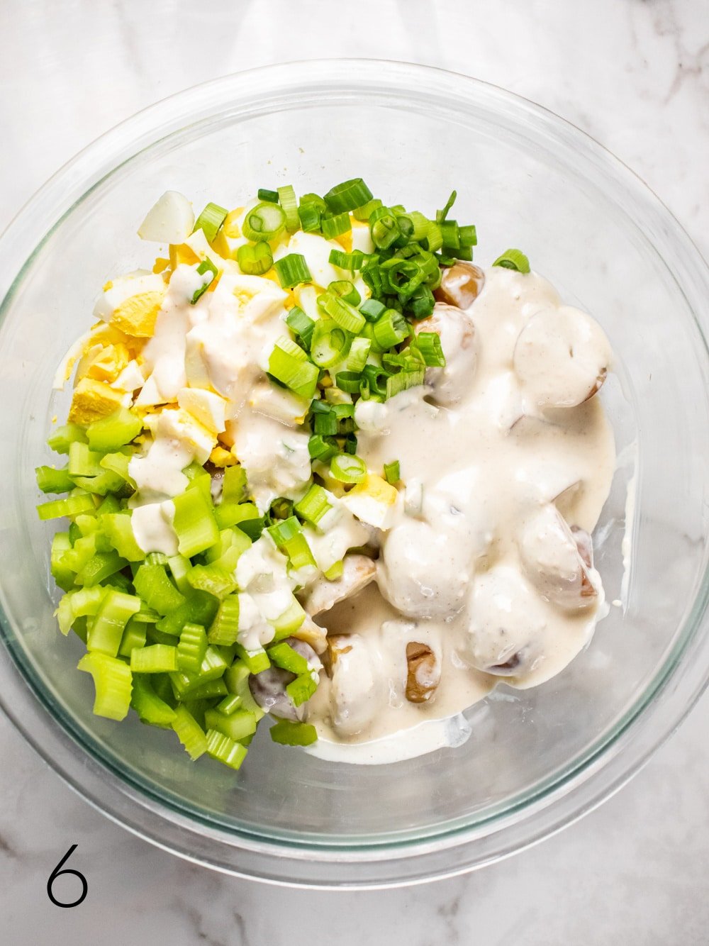 potato salad ingredients in a mixing bowl with yogurt
