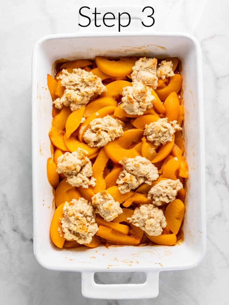 sliced peaches in a casserole dish with dough chunks on top