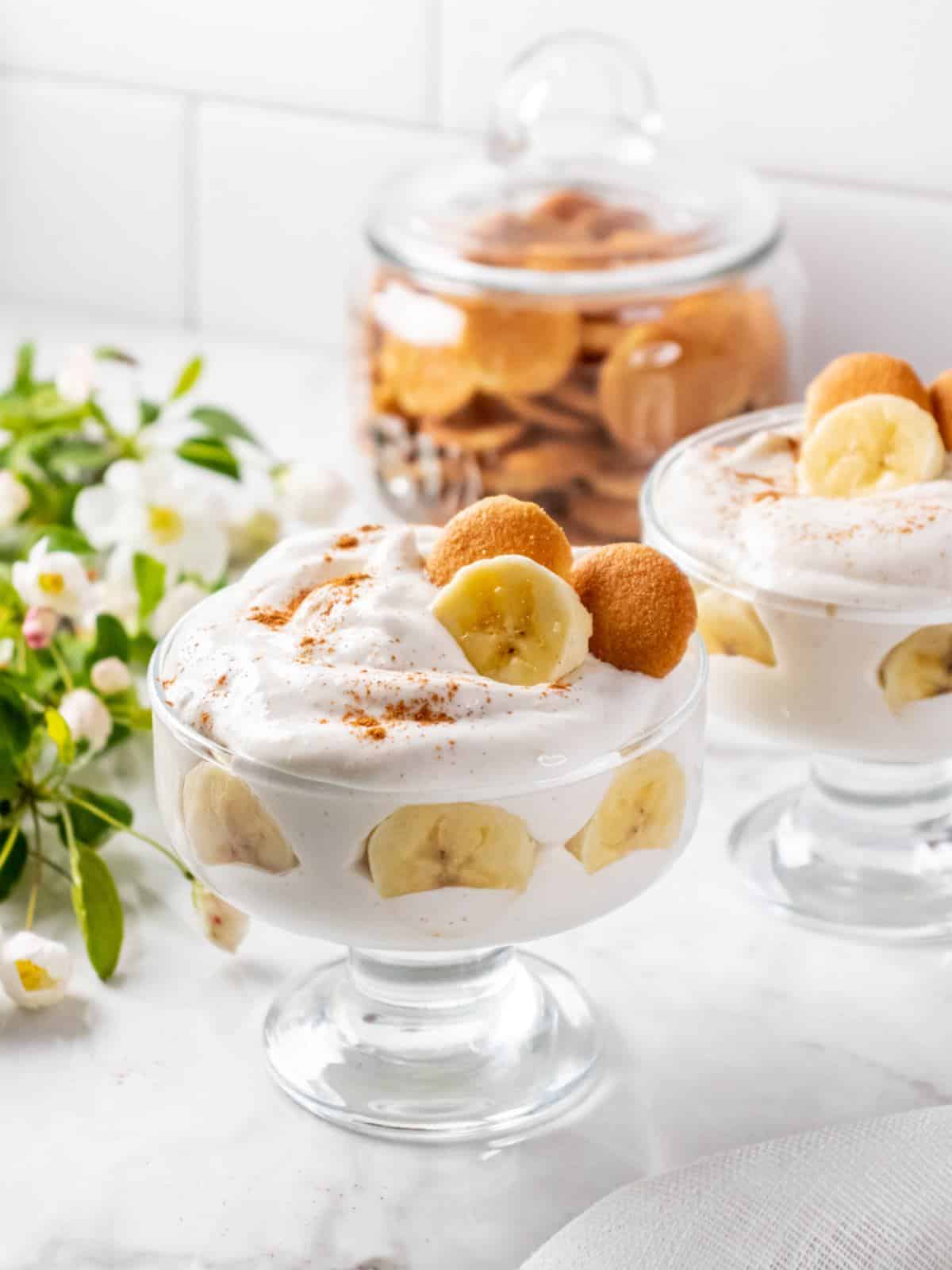 Clear glass with healthy banana pudding with wafers and banana slices on top.