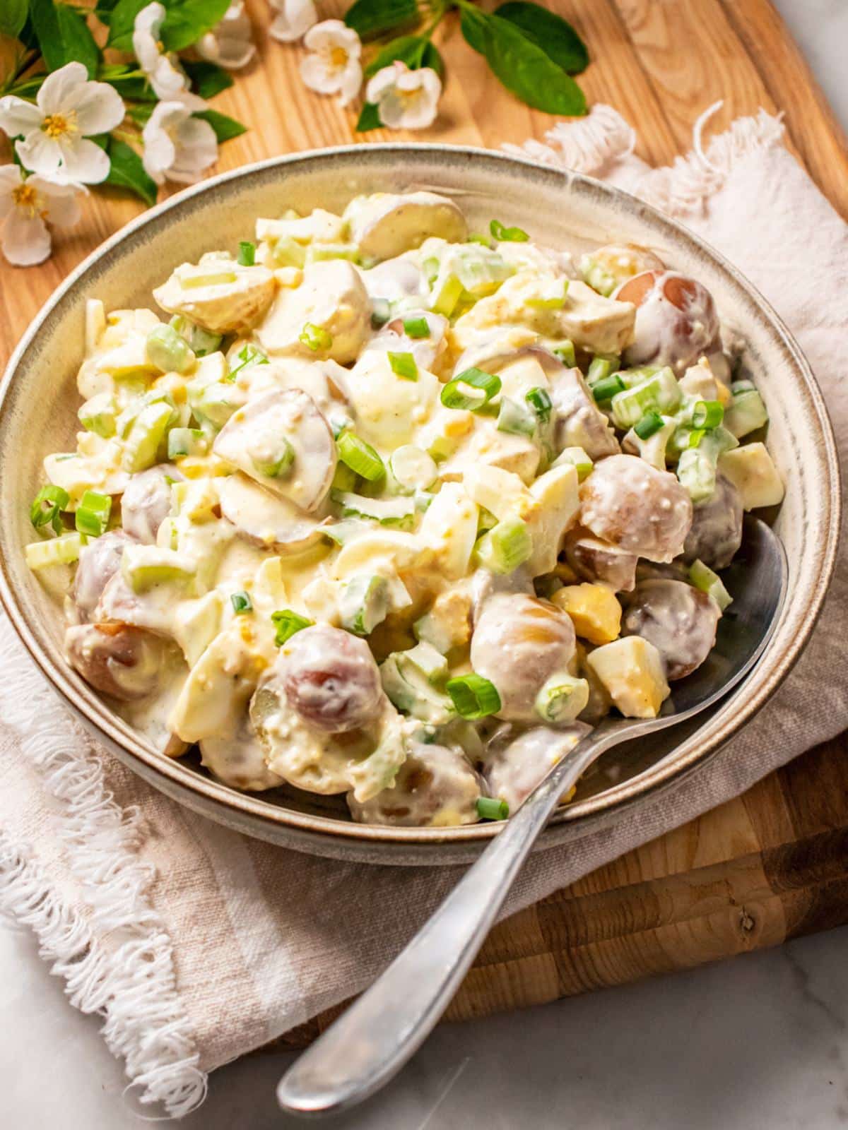 A bowl of healthy potato salad with a spoon resting on the bowl.