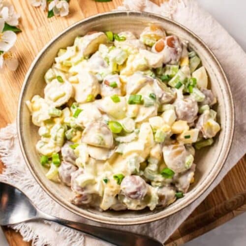 Healthy potato salad in a tan bowl on a table with a linen napkin underneath.