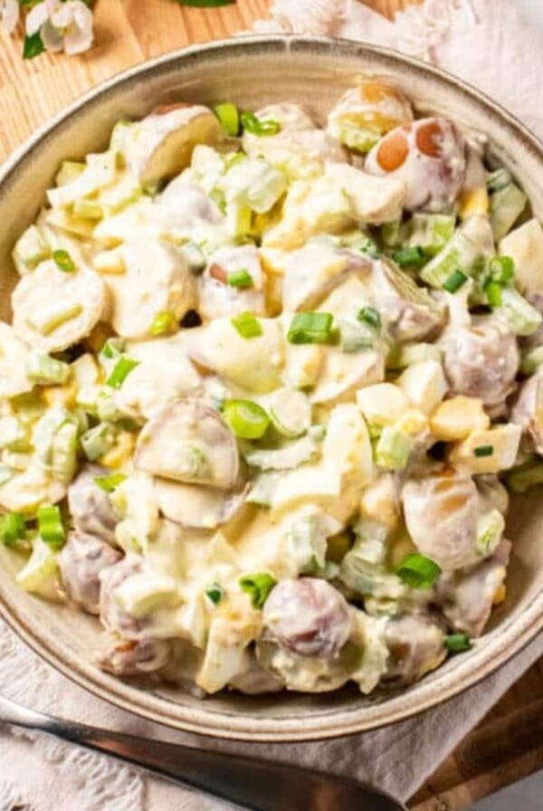 Healthy potato salad in a tan bowl on a table with a linen napkin underneath.