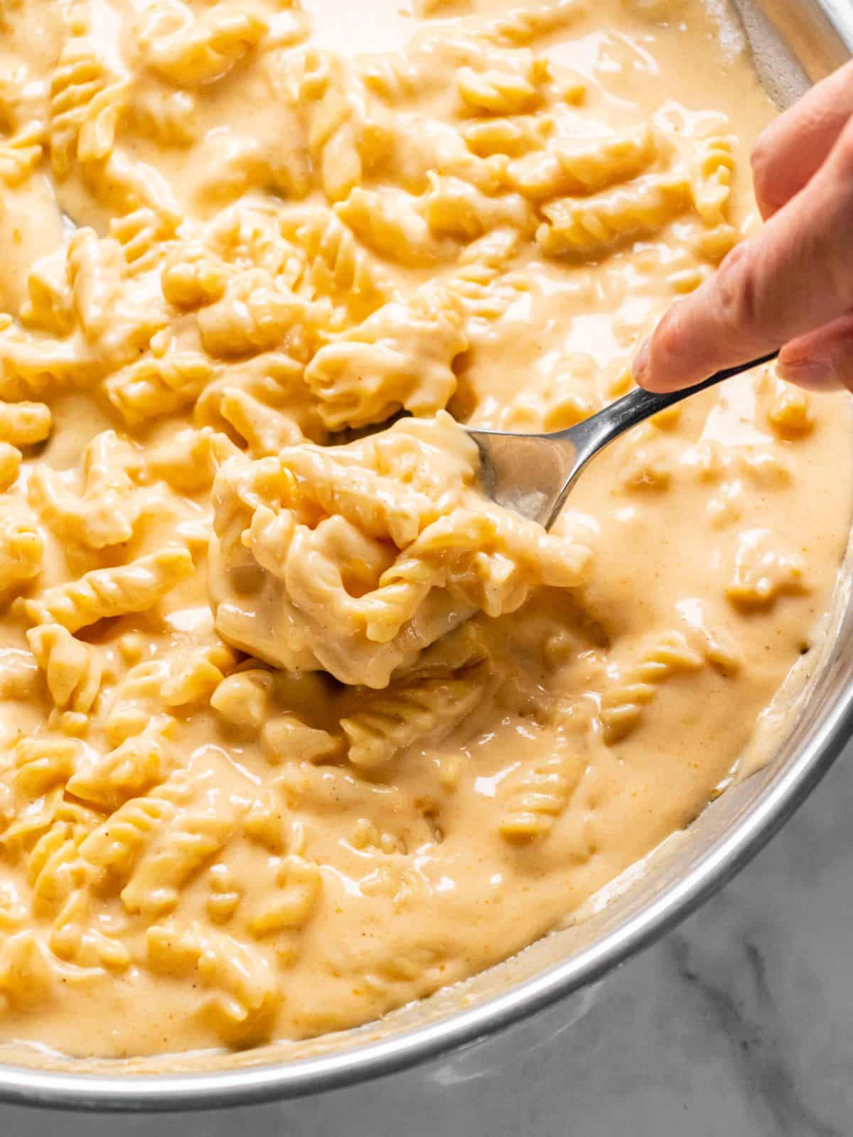 A spoon lifting up a serving of healthy mac and cheese.