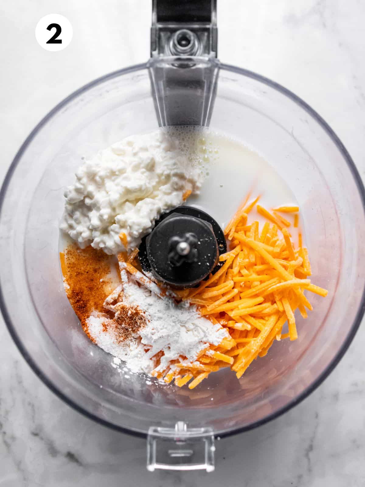 Food processor with cottage cheese and shredded cheese to make healthy mac and cheese.