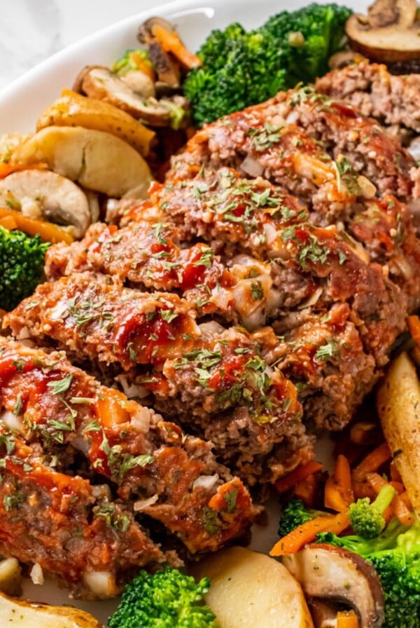 A 1-lb meatloaf sliced on a platter with vegetables.