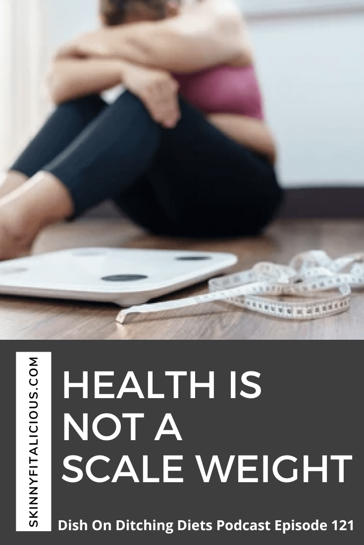 woman in blue leggings and a pink sports bra sitting on the floor with a arms crossed and a scale.