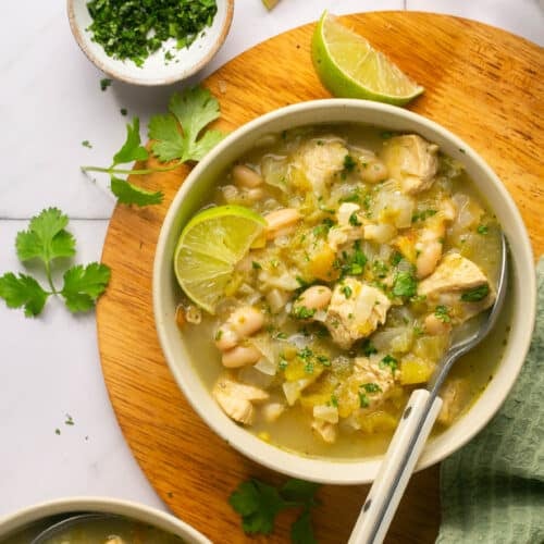 white bowl with chicken soup on a cutting board.