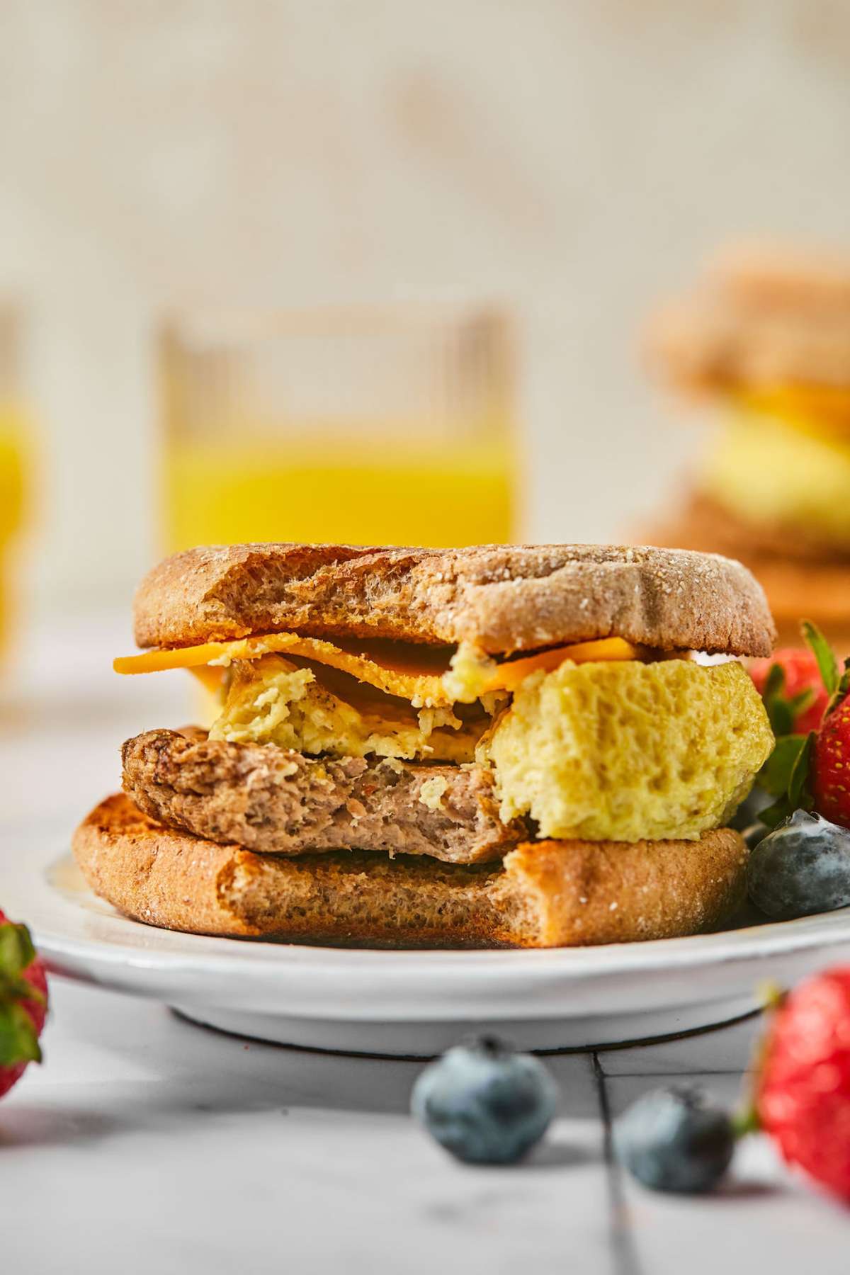 A high protein breakfast sandwich with a bite missing on a plate on the table.