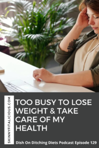 woman in a tan top with a brown cardigan holding her hand to her head sitting at a desk with a computer.