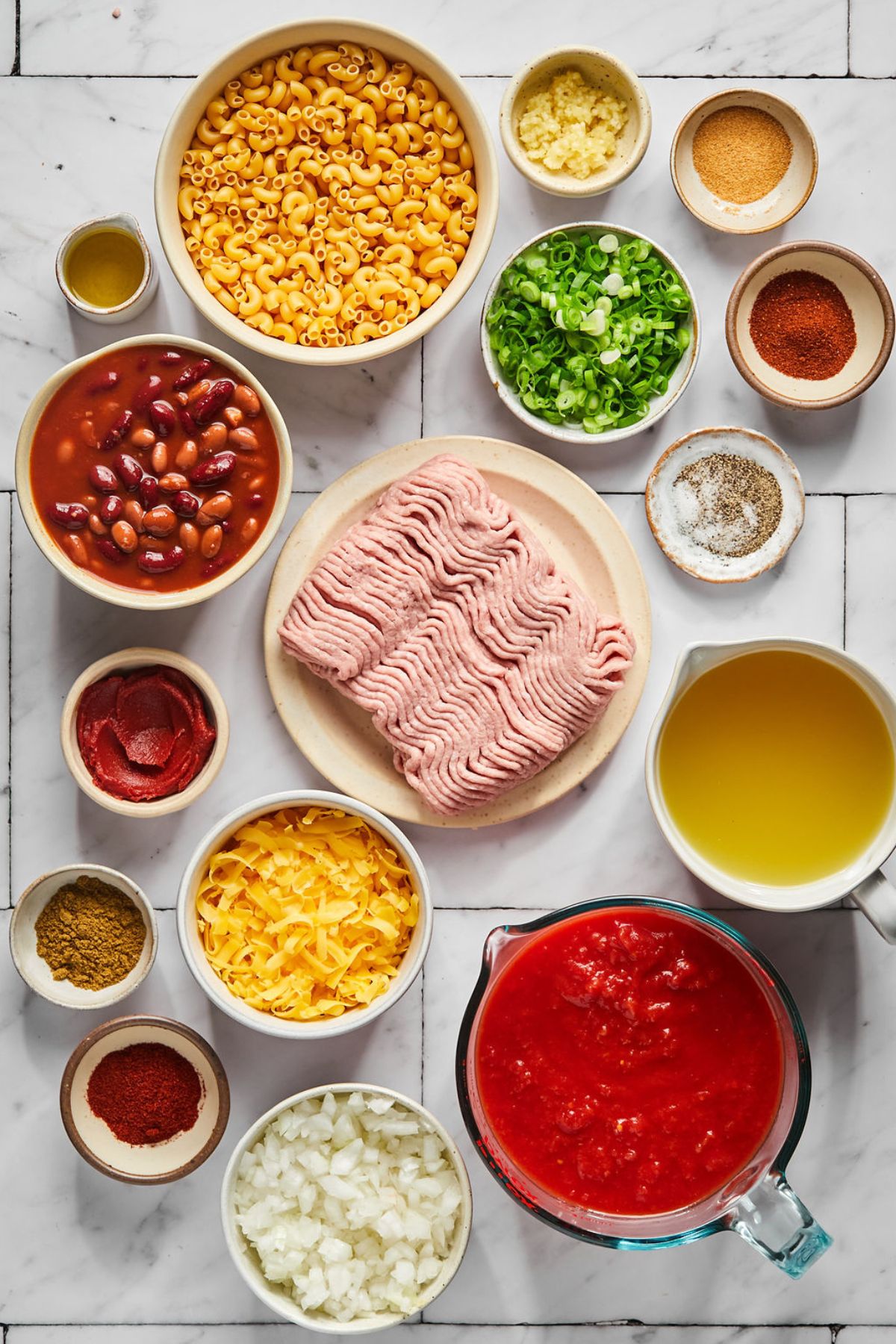 Bowls of ingredients to make high protein chili mac spread out on the counter before preparing.