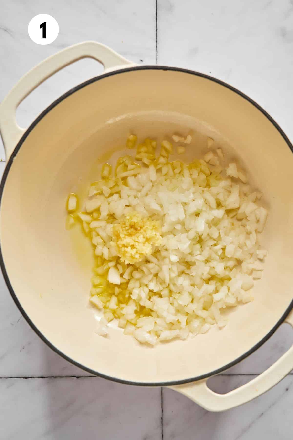 Onions and garlic added to a dutch oven to cook.