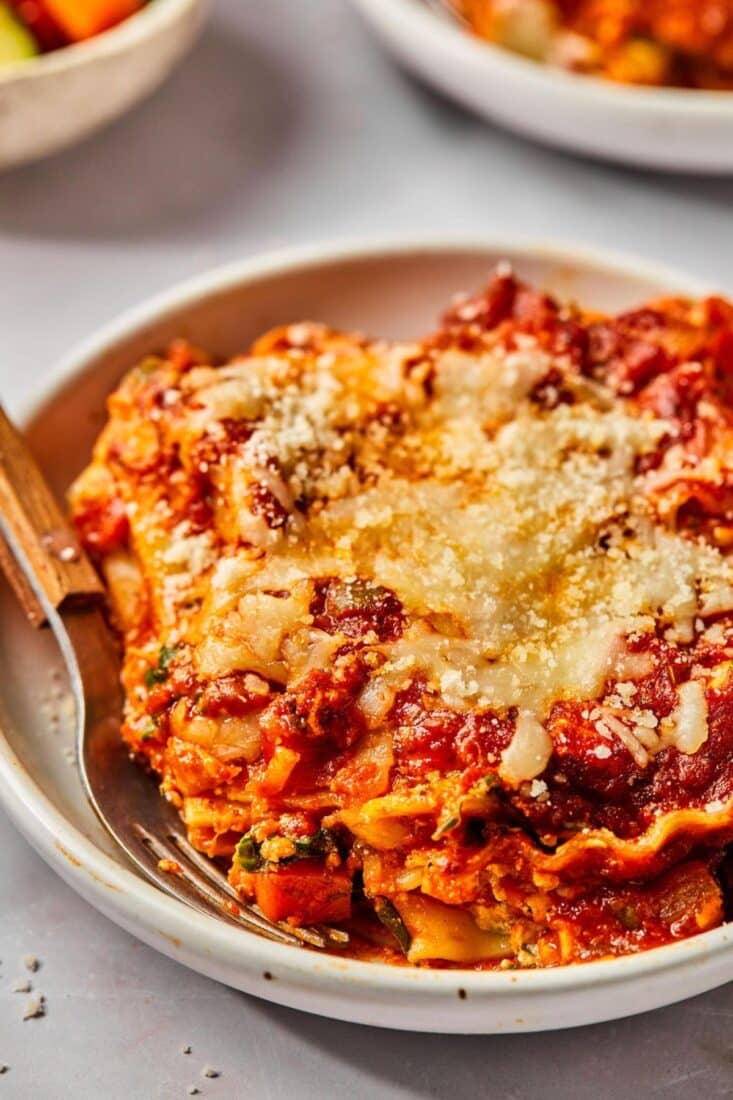 High protein vegetarian lasagna slice served up in a white bowl on the table.