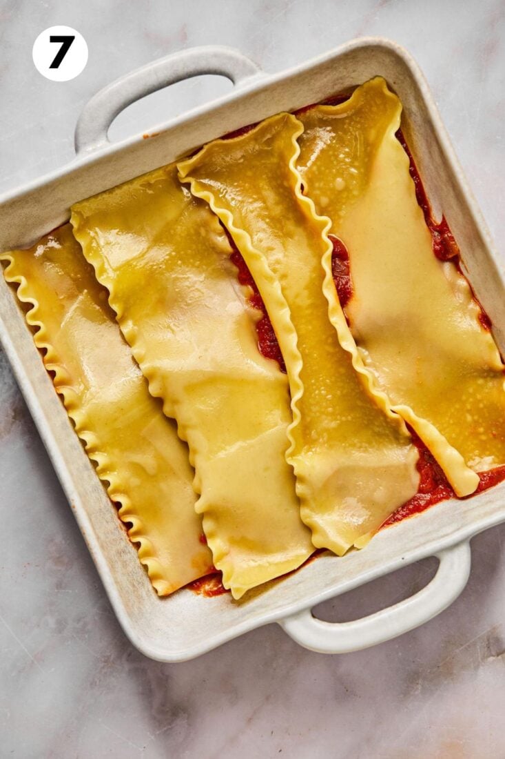 Sauce and noodles layered in a casserole dish.