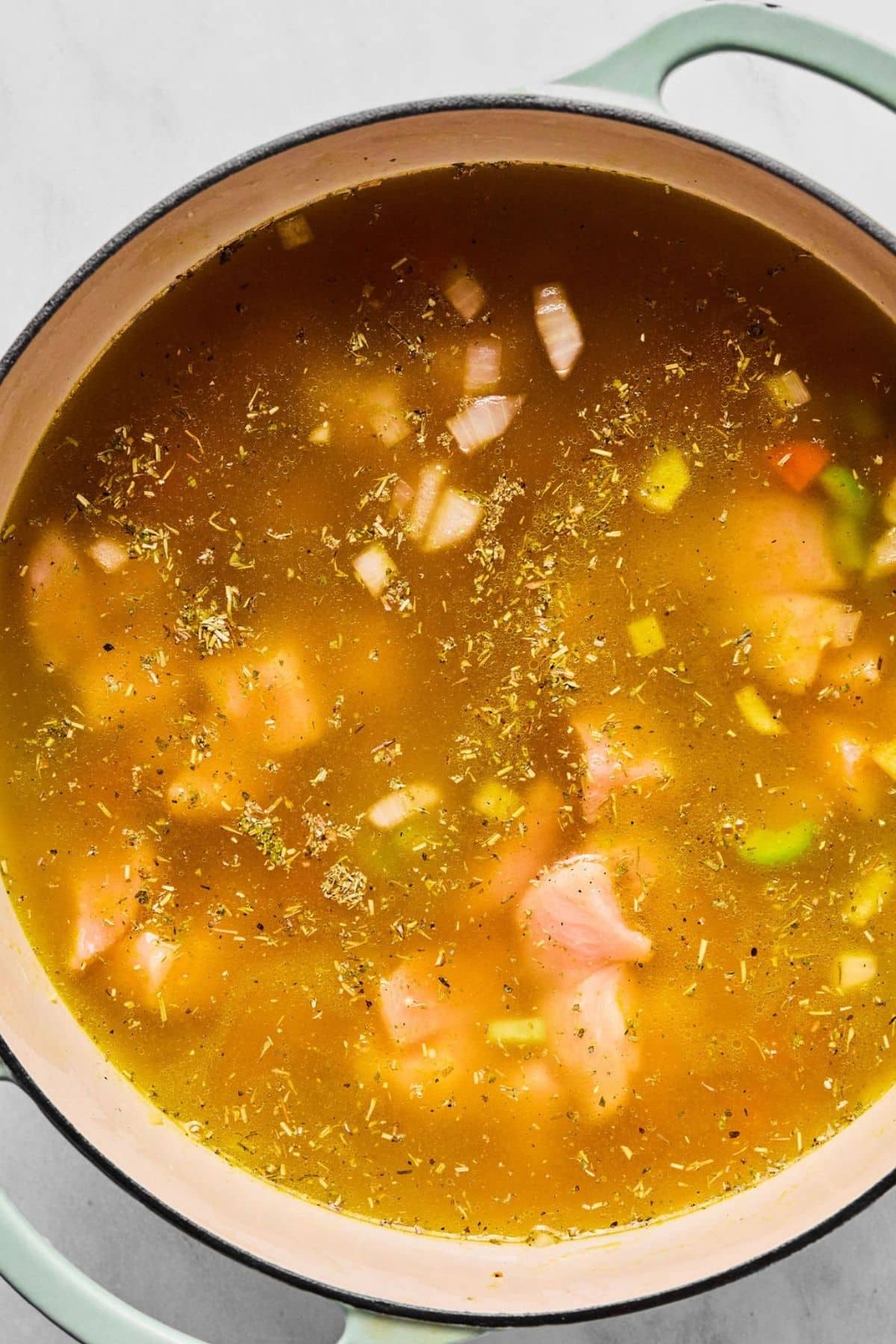 Chicken, seasonings and broth added to the pot.
