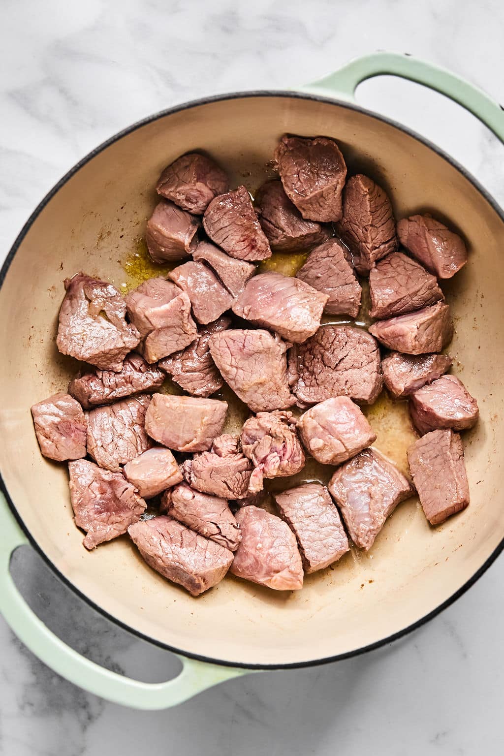 Chunks of beef browning in a pot.