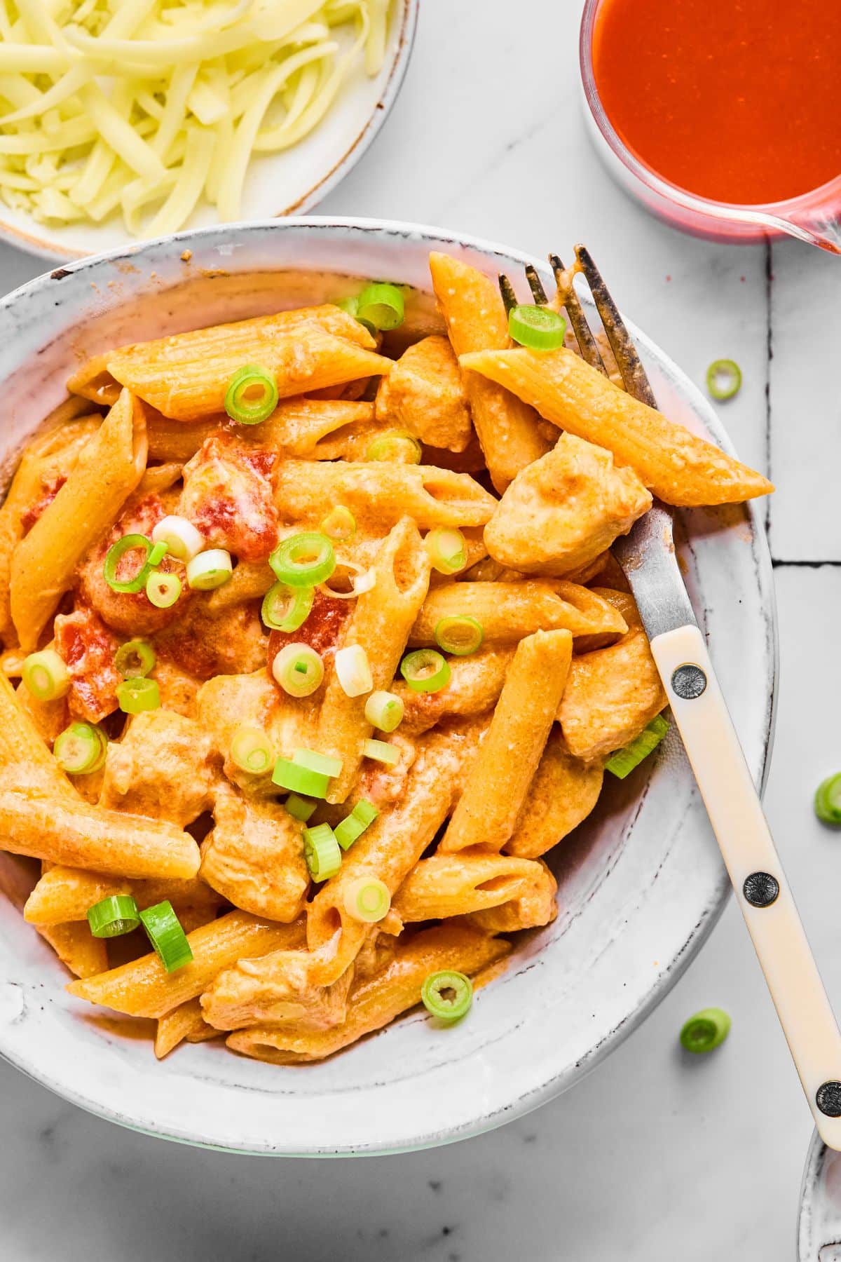 A plate of healthy buffalo chicken pasta with a fork resting on the edge of the plate.