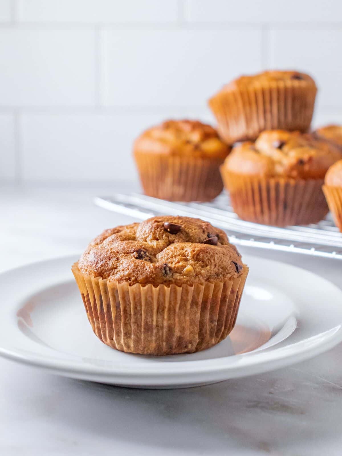 Protein muffin on a plate with more on a platter in the background.