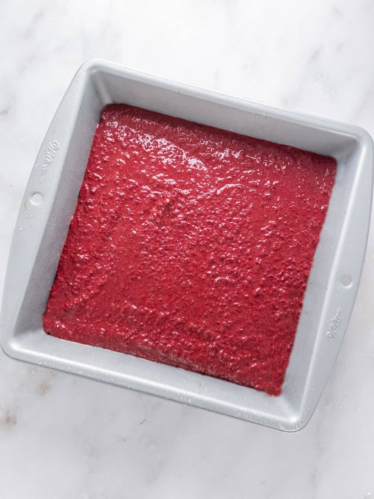 Brownie batter put into a cake pan.