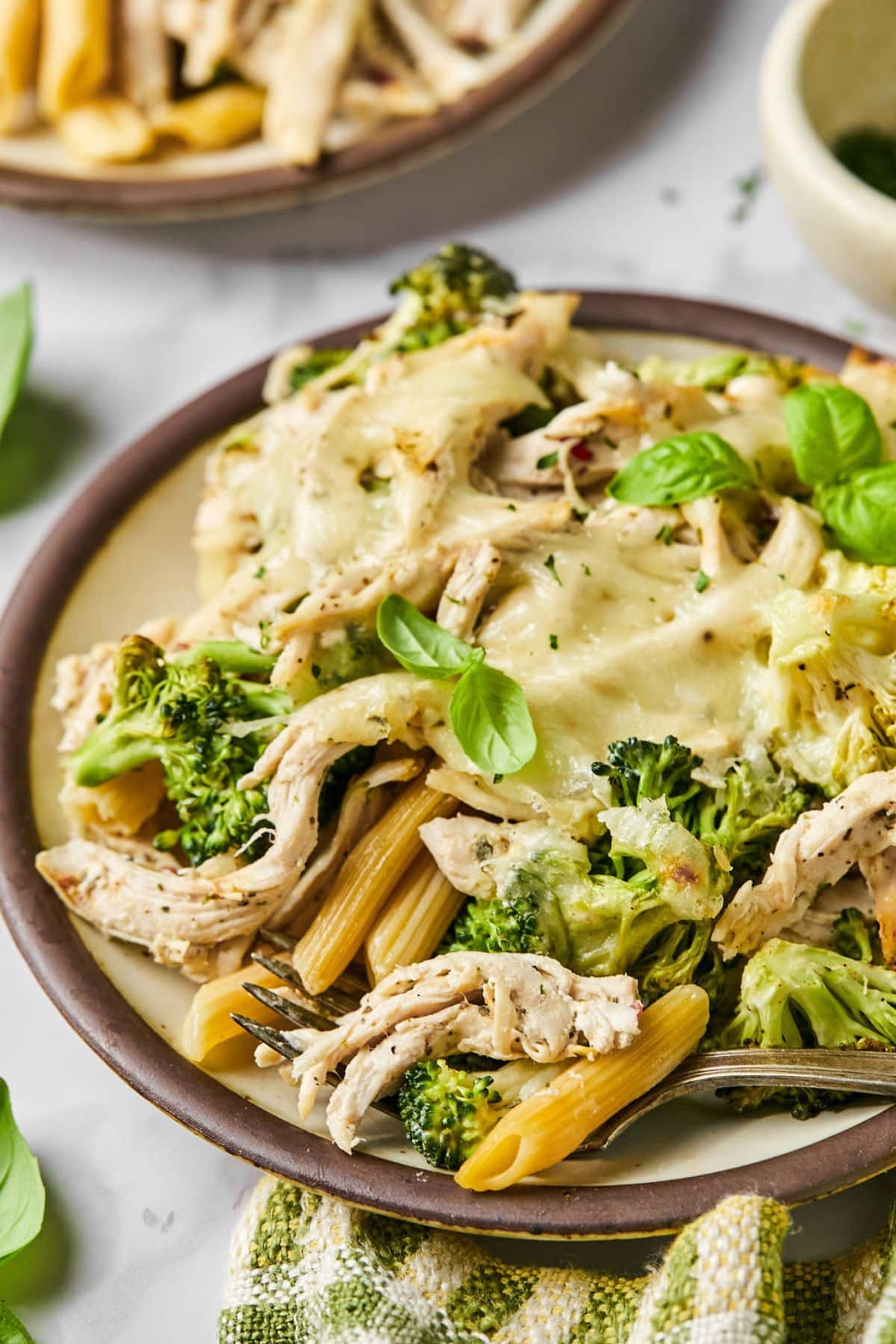 A plate with chicken, broccoli, pasta and cheese.