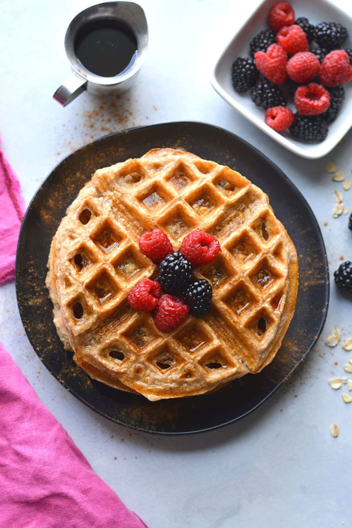 Cottage cheese waffles on a plate with berries on top.