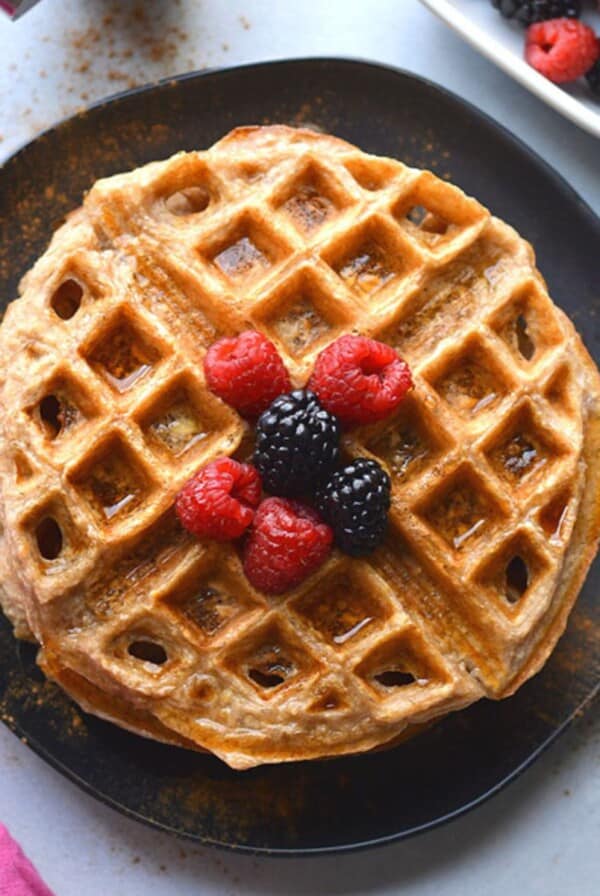 Cottage cheese waffles with raspberries and blackberries on top on a plate.