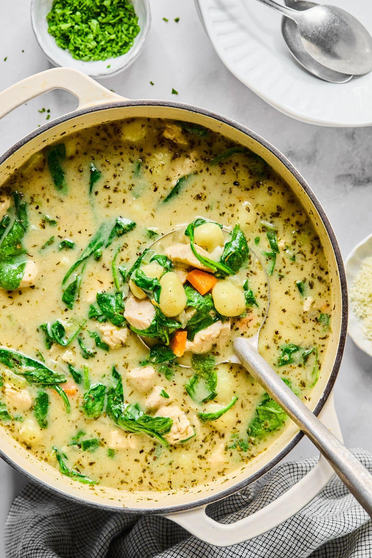 A pot of creamy gnocchi soup with a ladle scooping up a serving.
