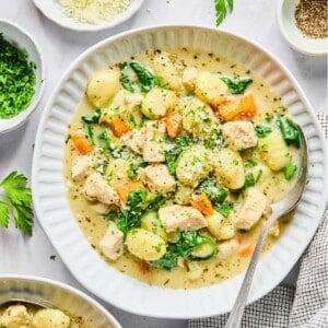 A bowl of creamy gnocchi soup with a spoon resting on the side.