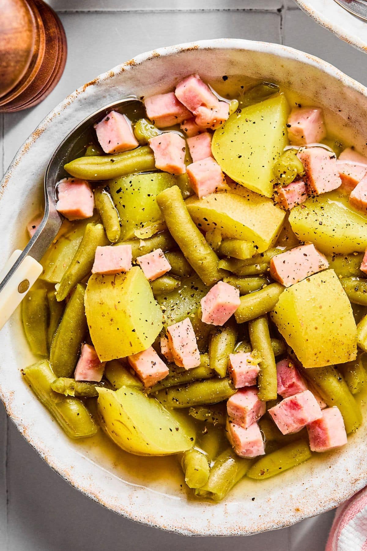 A bowl filled with ham green beans and potatoes.