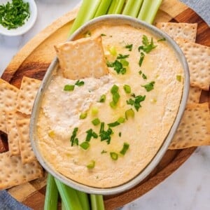 A cracker dipping into a dish of hot crab dip.