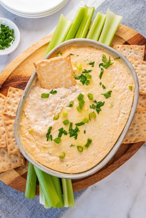 A cracker dipping into a dish of hot crab dip.