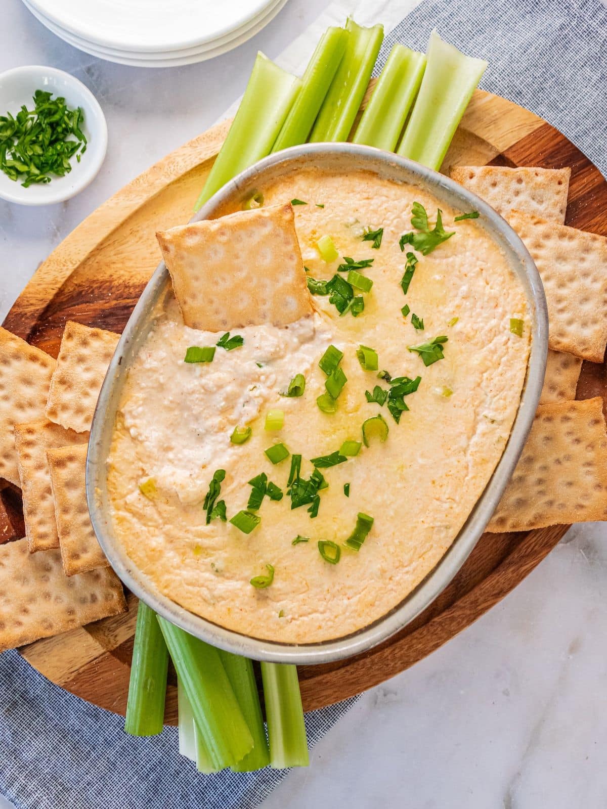A cracker dipping into a dish of hot crab dip.