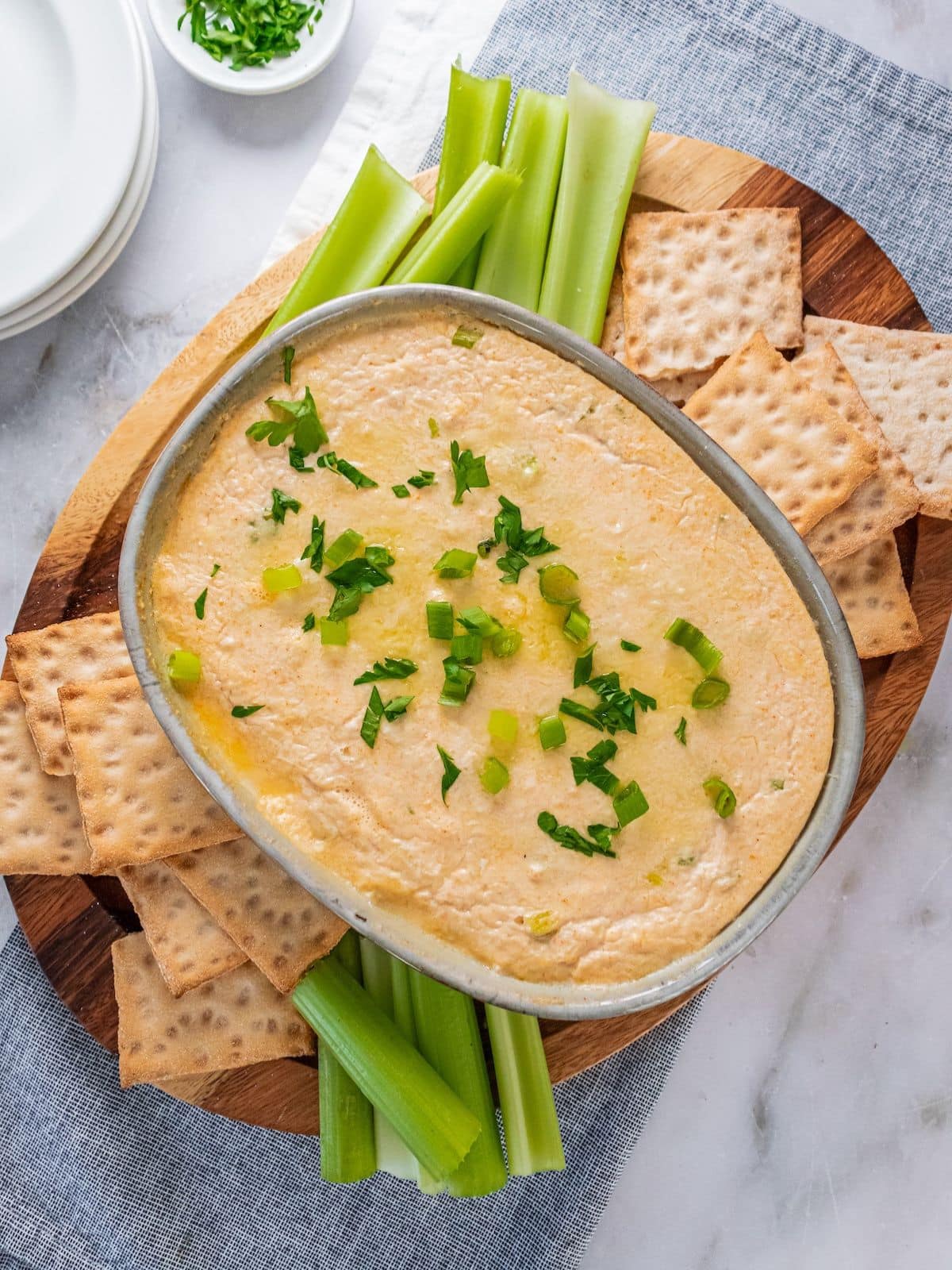 Baked crab dip served with celery sticks and crackers.