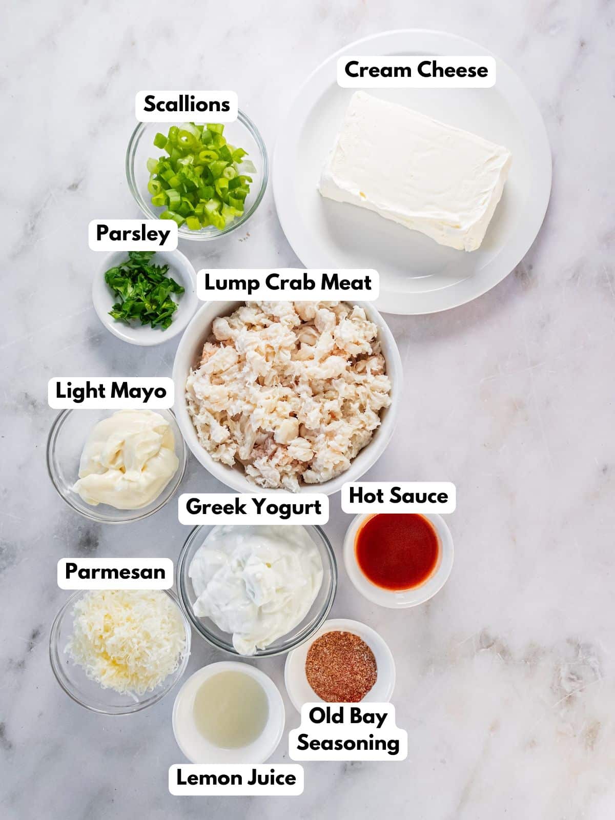Ingredients to make hot crab dip on a table in bowls.