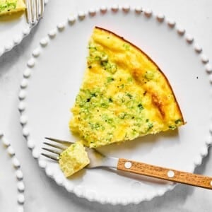 A plate with a piece of quiche without crust taken off with a fork.