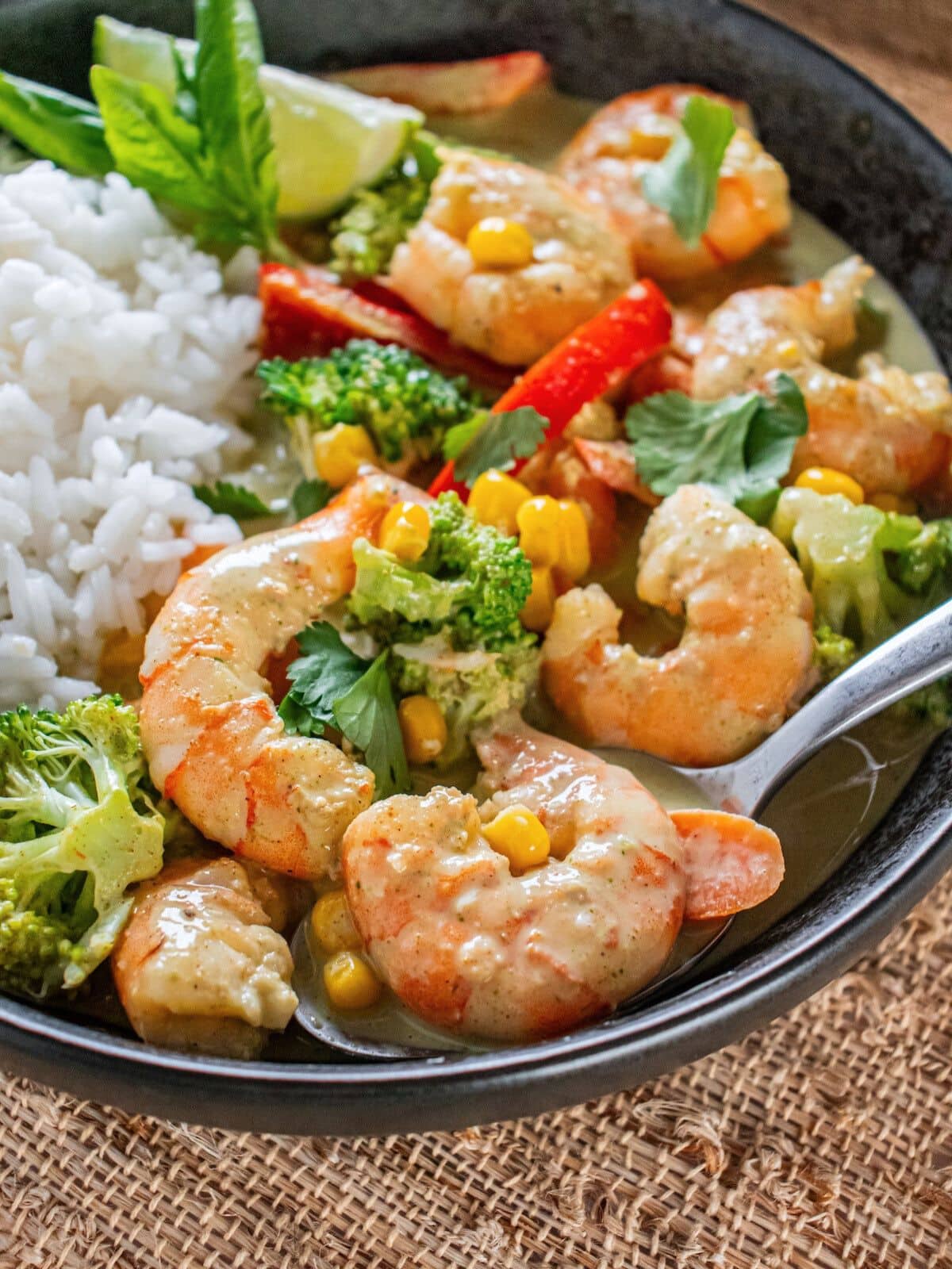 A bowl of shrimp curry with some rice.