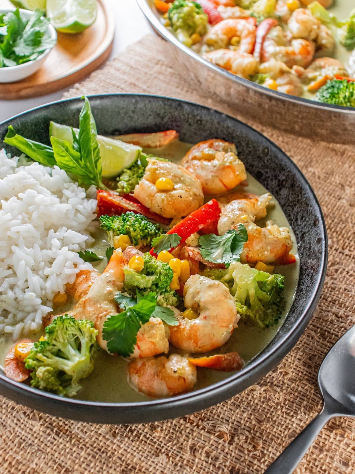 A dish of Thai shrimp curry on a table with a skillet of more.