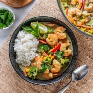 A bowl of shrimp curry recipe with a spoon to the side and the pot holding more.