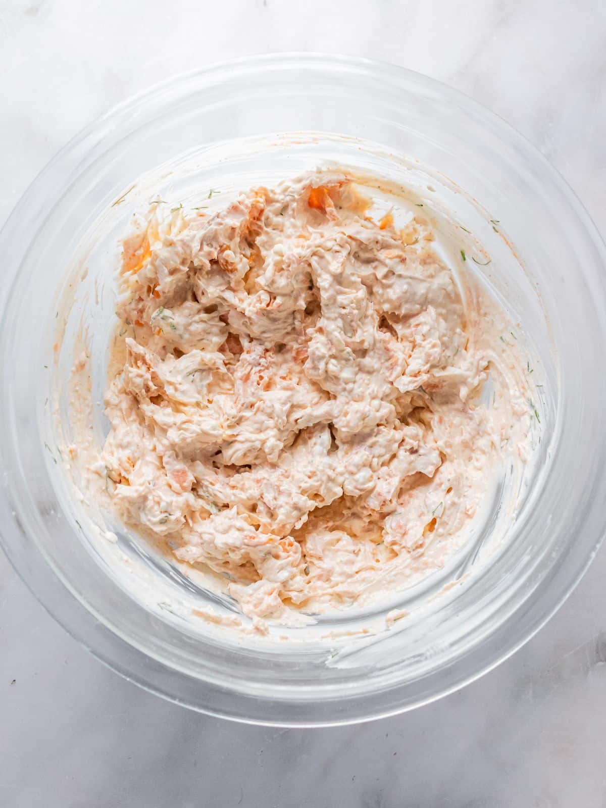 Flaked smoked salmon added to the bowl of seasoned cream cheese.