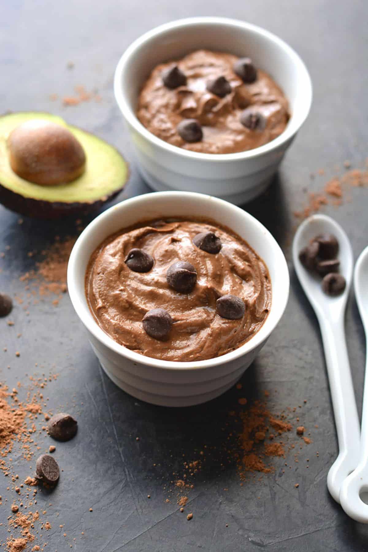 Two bowls of chocolate avocado mousse on a table.