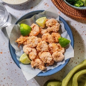 Baked coconut shrimp on parchment paper in a bowl.