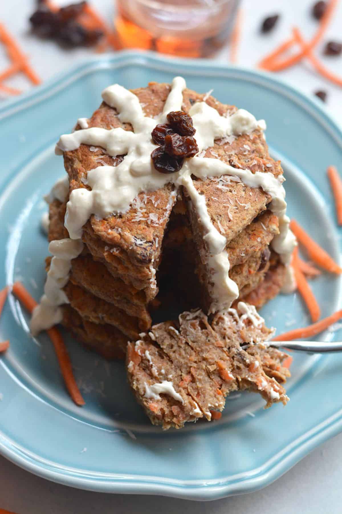 A stack of carrot cake pancakes with slice removed on a fork.