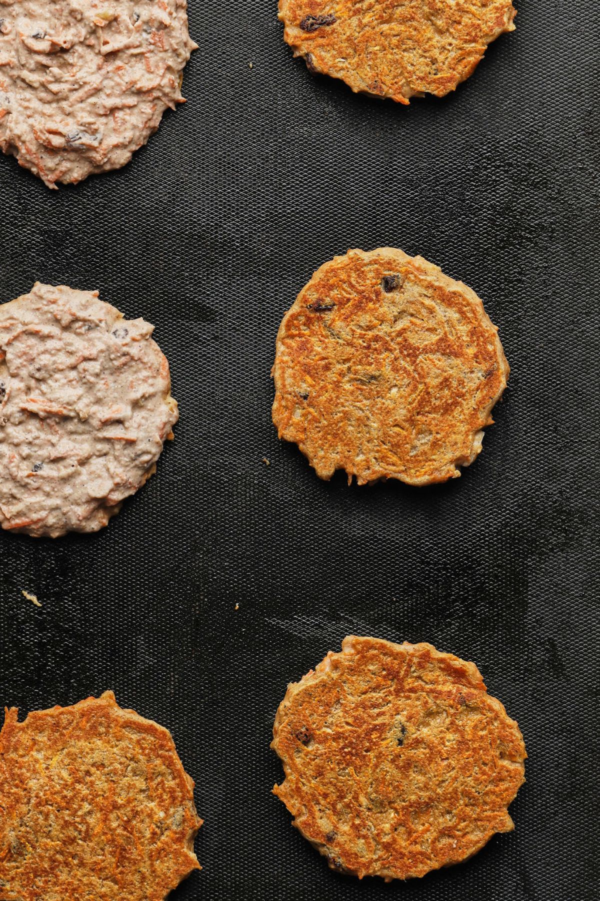 Carrot pancakes cooked and being flipped.