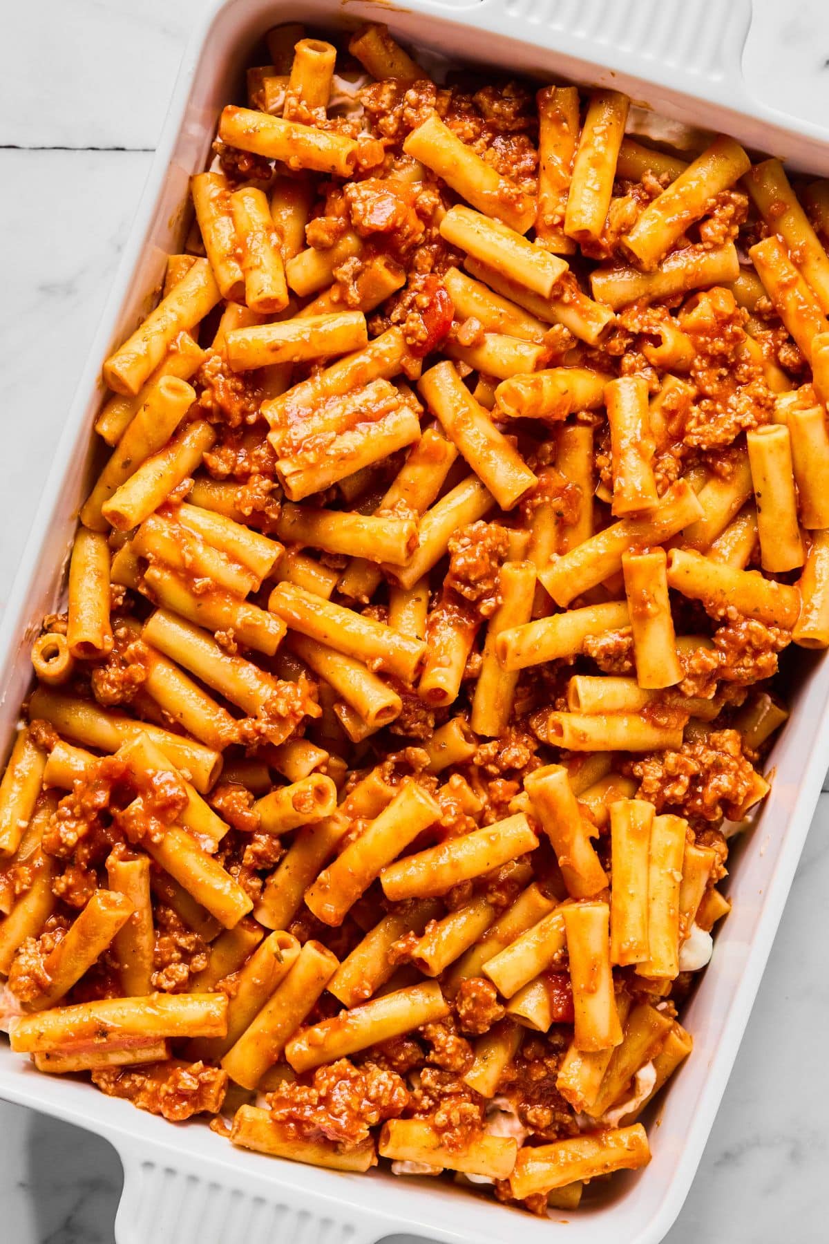 Another layer of pasta with meat sauce added on top of the cheese layer.