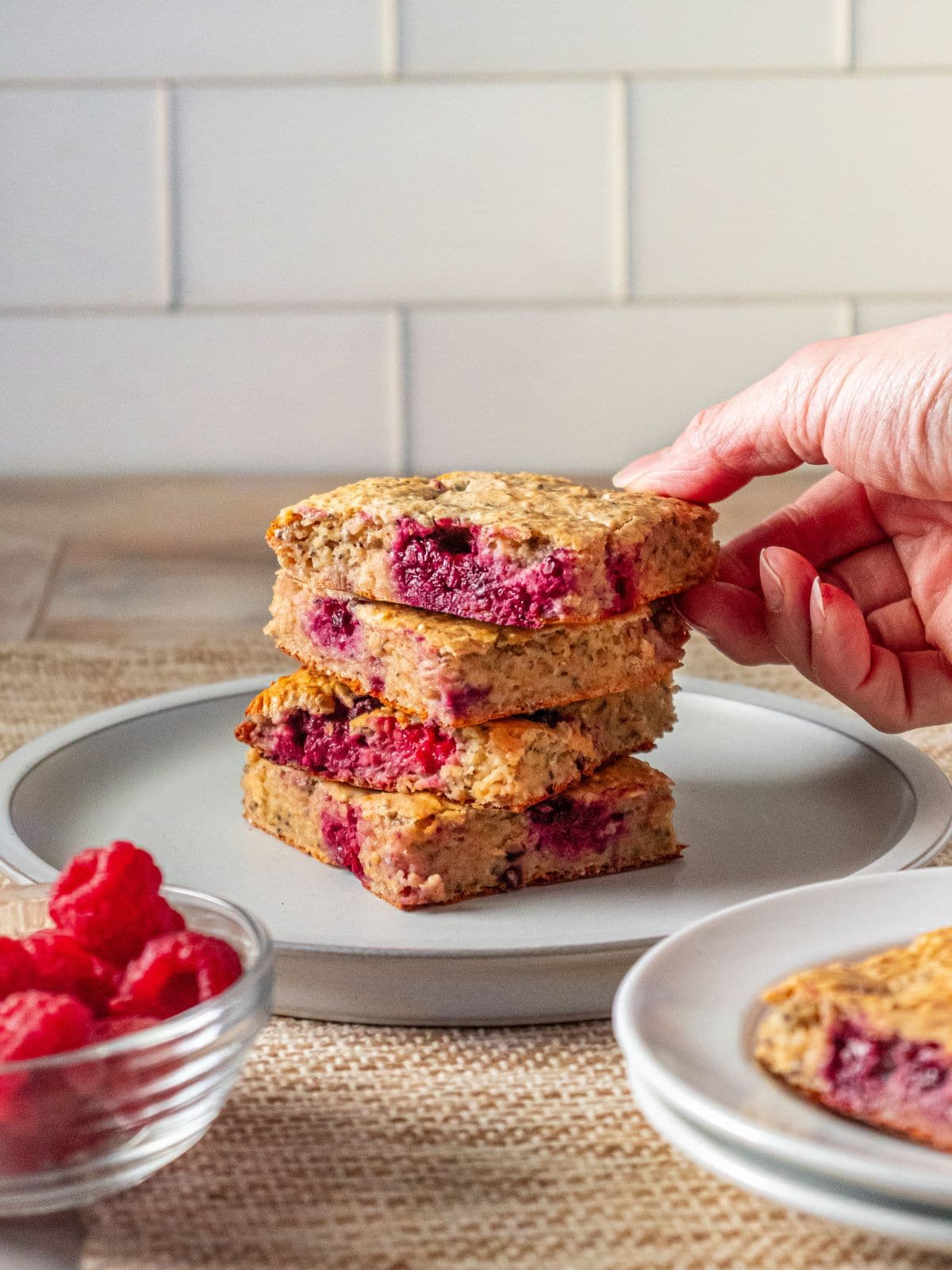 A hand picking up some cottage cheese bars off of a plate.