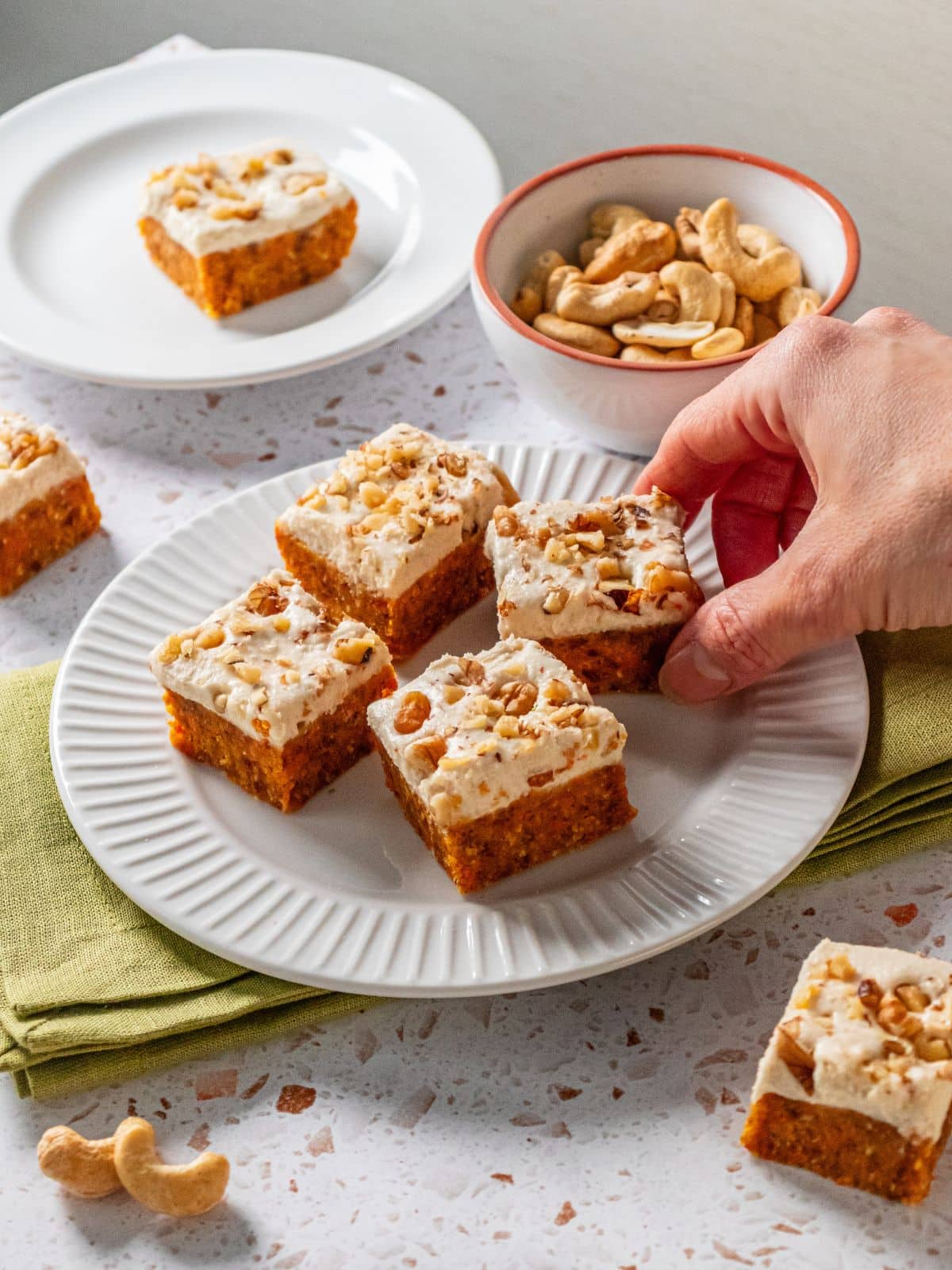 A hand picking up a piece of gluten-free carrot cake.